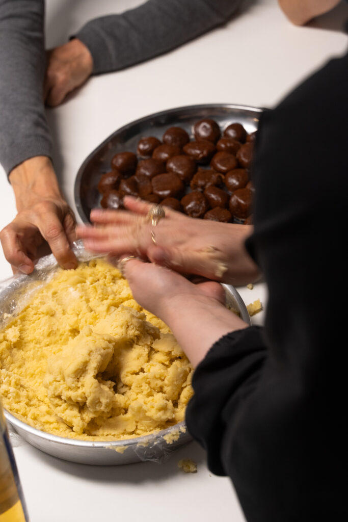 Aus einer Schüssel mit Teig formt eine Frau mit den Händen Rollen.