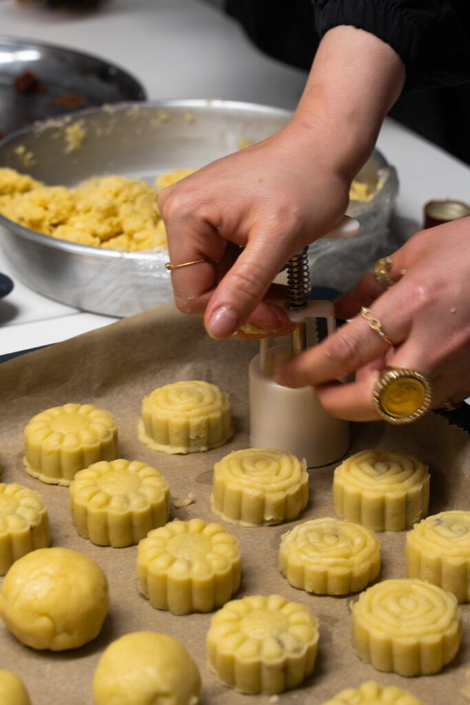 Mit einem besonderen Ausstecker werden Kekse auf einem Backbleck geformt.