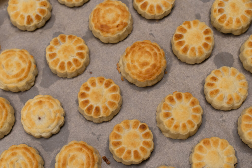 Auf einem Backbleck liegen Kekse in Blumenform.