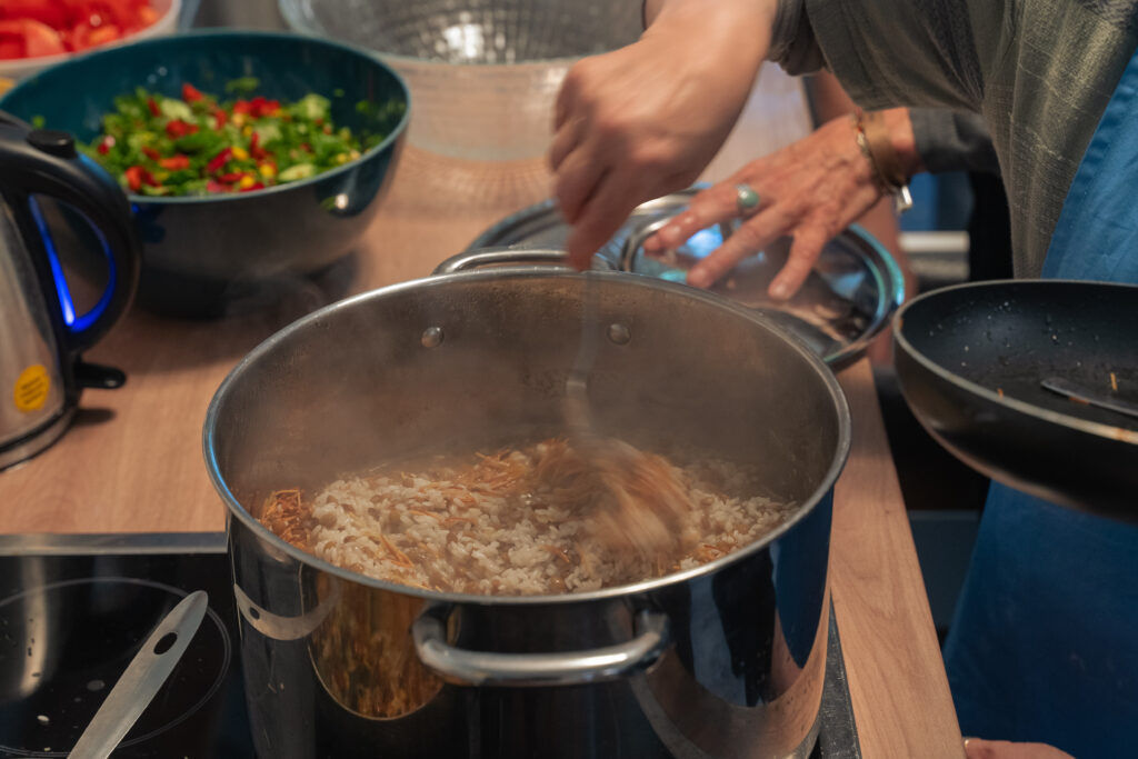 In einem großen Top wird mit einem Löffel Reis mit Linsen vermischt.
