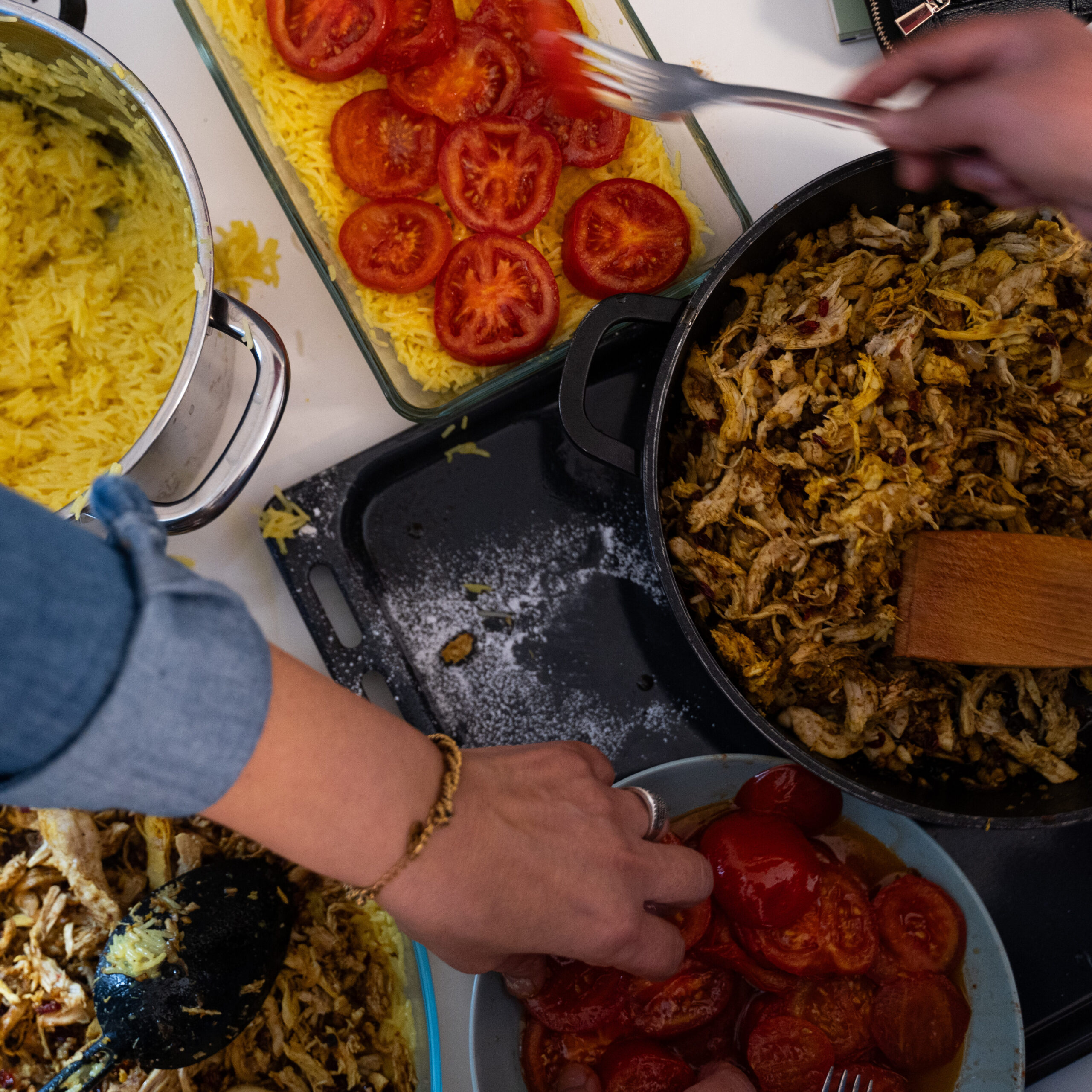 Perspektive von oben, wie Reis mit Tomaten und Fleisch in eine Auflaufform geschichtet wird. 