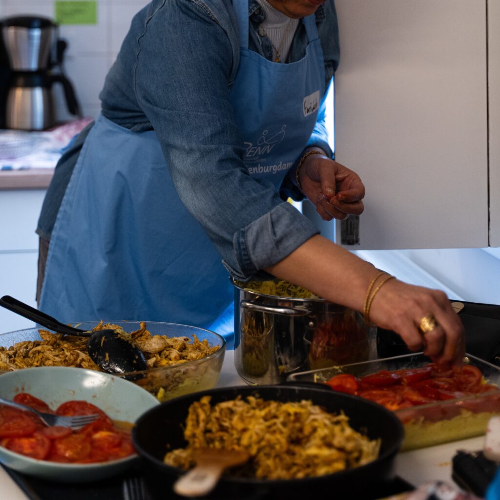 Eine Frau schichtet Tomaten mit Reis  und Fleisch in eine Auflaufform.